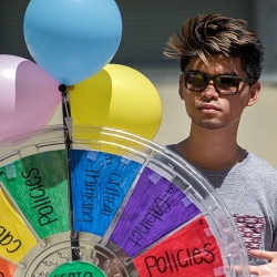 young man standing next to a colored balloons